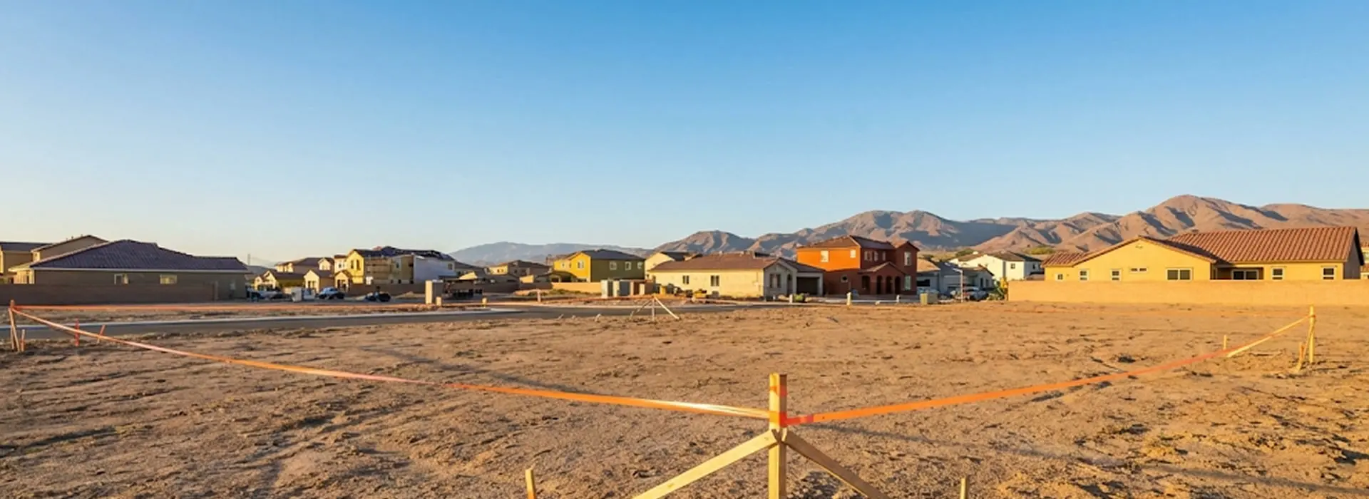 Terreno baldío con estacas de medición y ciudad al fondo